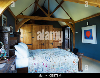 Armadi a muro non verniciata con porte in legno blu scuro camera da letto con travi in legno a vista e legno intagliato bed Foto Stock