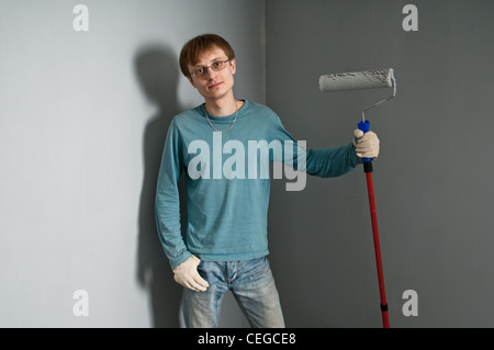 Giovane uomo con spazzola in posa contro solo parete dipinta Foto Stock