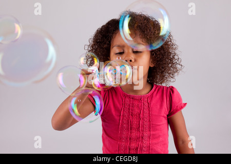 Carino piccolo African American Girl soffiando bolle di sapone Foto Stock