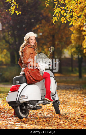 Ritratto della splendida ragazza su scooter che pongono nel parco Foto Stock