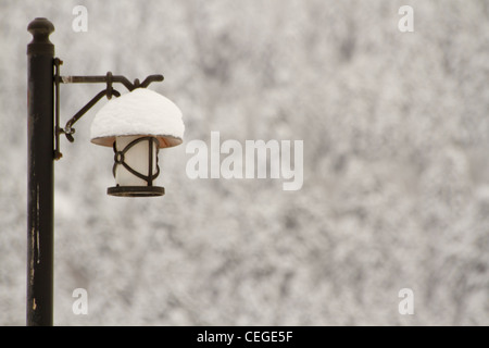 Lampada di illuminazione sul palo di legno di un parco in inverno Foto Stock