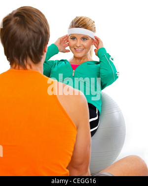 Personal trainer sport aiutando ragazza sani rendendo crunch addominale sulla sfera di fitness Foto Stock