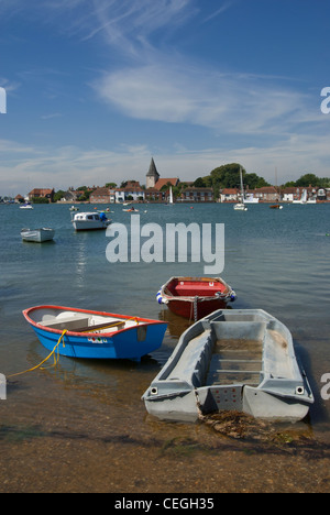 Barche colorate nel torrente a Bosham con il villaggio in background in una calda giornata estiva con cielo blu Foto Stock