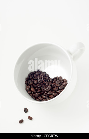 Chicchi di caffè a forma di cuore all'interno di una grande tazza di porcellana bianca Foto Stock