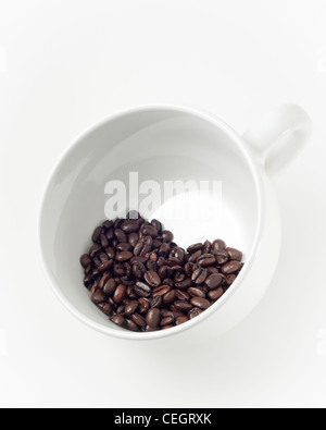 Chicchi di caffè a forma di cuore all'interno di una grande tazza di porcellana bianca Foto Stock