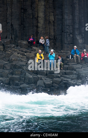 Turisti, visitatori e la gente a piedi e sedersi lungo le colonne di basalto sull isola di Staffa sul Ebridi Interne della Scozia. Foto Stock