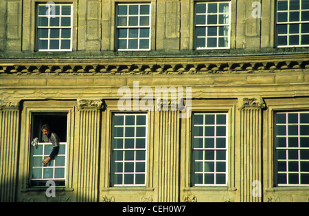 Un uomo appoggiato al di fuori di un vecchio edificio georgiano per pulire la finestra windows nella città di Bath, Somerset, Inghilterra, Regno Unito. Foto Stock