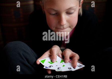 Di undici anni ragazza con un mazzo di carte, mostrando la sua mano. Foto Stock