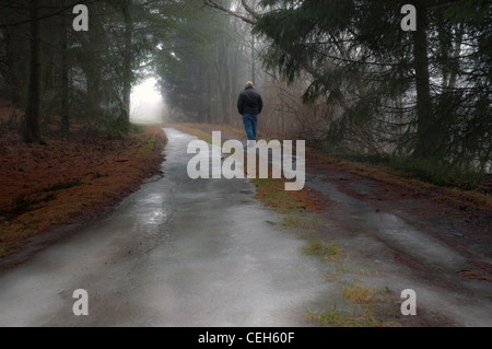 Un uomo che cammina da sola su una strada ghiacciata Foto Stock