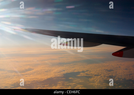 Vista da finestra sede dell'ala di aeroplano sopra lo strato di nuvola al tramonto Foto Stock