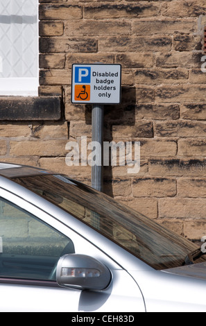 Badge disabili titolari segno parcheggio dietro la macchina parcheggiata. Foto Stock