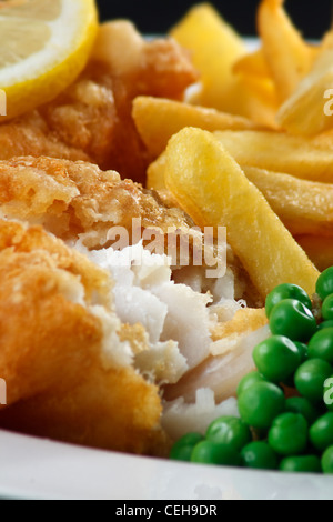 Close up di pesce e patatine con piselli e una fettina di limone. Un britannico tradizionale piatto di mare Foto Stock