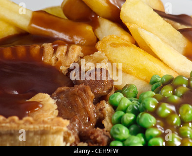 Close up della bistecca torta e patatine con piselli e sugo di carne. Un tradizionale piatto britannico Foto Stock