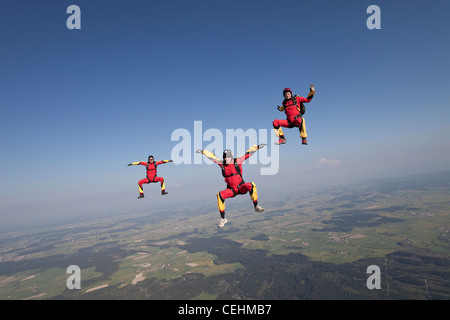 Skydivers sono battenti testa fino all'interno di una squadra e provare il sit fly posizione su uno spettacolare paesaggio di erba scenario. Foto Stock