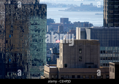 Una vista tra Manhattan magma caotico di grattacieli e edifici inferiore, con Ellis Island in distanza. Foto Stock