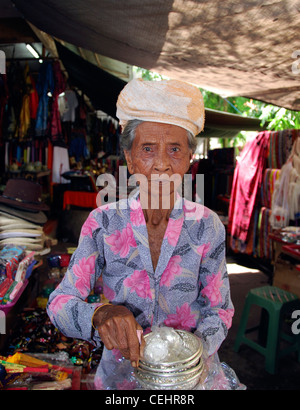 Vecchia donna che offre piatti d'argento nel mercato locale, Ubud, Bali, Indonesia Foto Stock