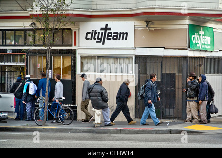 In serata, persone senza fissa dimora di entrambi i sessi immettere CityTeam Ministeri su 6th Street di San Francisco. Foto Stock