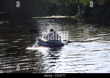 Un uomo che indossa un giubbotto di salvataggio pagaie un kayak lontano dalla fotocamera, spruzzi d'acqua da paddle, il fiume Avon, Bidford on Avon. Foto Stock