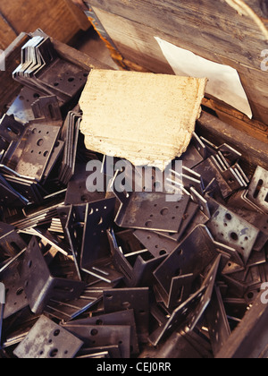 Un pezzo di cartone disordinato come sfondo per il vostro testo posizionato su una pila di grungy dettagli metallici in una fabbrica Foto Stock