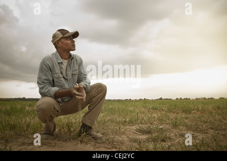 African American Farmer controllando la sporcizia nel campo Foto Stock