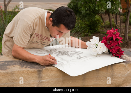 Giovane maschio ispanica artista lavora sul disegno a matita a un esterno di Plaza di San Antonio, Texas Foto Stock