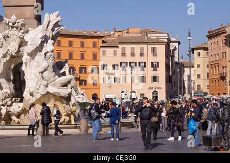 Visitatori e turisti riempiono la piazza in ciottoli di Piazza Navona con la Fontana dei Quattro Fiumi - Fontana dei Quattro fiumi Foto Stock