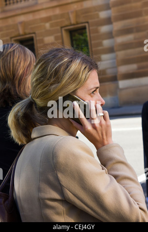 Imprenditrice parlando su Apple iPhone Sydney business district, Australia Foto Stock