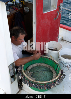 Grecia CICLADI sikinos un pescatore baiting una lunga fila di ganci Foto Stock