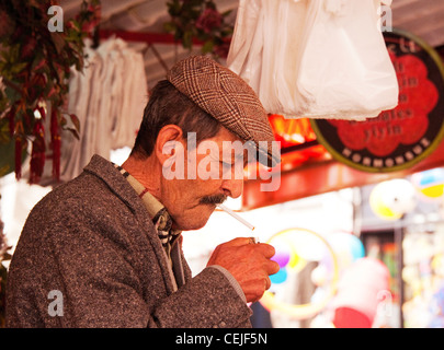 Bagno turco uomo nel mercato di sigarette di illuminazione, Ayvalik, Turchia Foto Stock