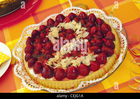 Festa di compleanno impostazione tabella con torta alle fragole decorata con mandorle a fette. Foto Stock