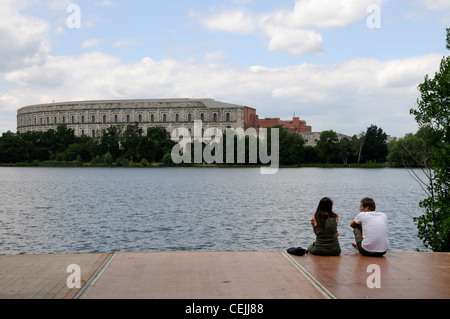 Di fronte ad un grande lago si trovano gli imponenti resti della Sala dei Congressi (Die Kongresshalle) nell'ex rally nazista di Norimberga, Baviera, Germania. Foto Stock