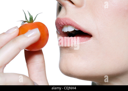 Femmina rosa da indossare lucidalabbra, mangiare pomodoro ciliegino Foto Stock