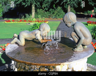 La scultura e la fontana dei due bambini che giocano nei giardini di valle di un parco pubblico in Harrogate North Yorkshire England Regno Unito Foto Stock