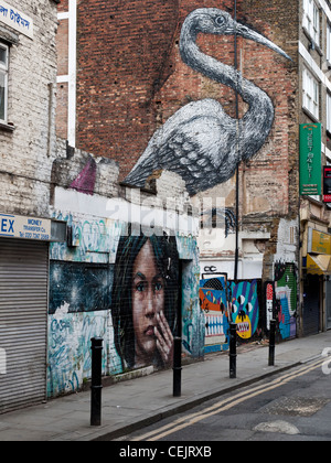 Arte di strada di un uccello dall'artista Roa in Hanbury Street , a est di Londra. L'illustrazione in primo piano è da artista Cosmo Sarson. Foto Stock