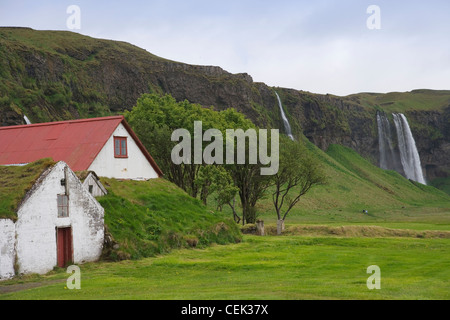Casa sul pascolo con cascata Seljalandsfoss, Seljalands, Sudhurland, Islanda Foto Stock