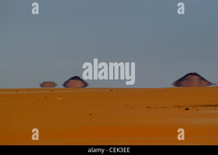 Deserto egiziano mirage nel deserto occidentale di Egitto - Sahara Orientale. Fata Morgana mirage con piramidale a formazioni di roccia. Foto Stock