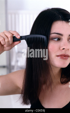 Passo per passo i capelli Updo femmina con brunette capelli, pettinare i capelli con i capelli neri pettine, c'erano pochi sorrisi, guardando al lato Foto Stock