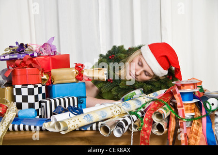 Donna vestita di Santa Claus costume dormire oltre il dono materiale di incarto Foto Stock