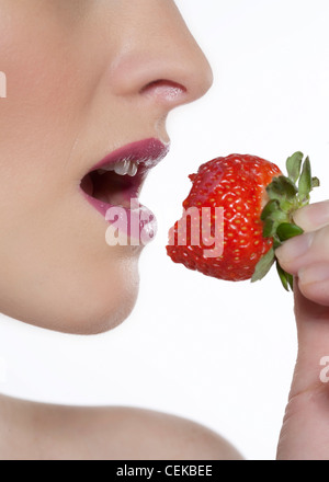 Femmina rosa da indossare lucidalabbra, mangiare una fragola, profilo a fotocamera Foto Stock