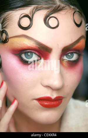 John Galliano Parigi Backstage Primavera Estate modello corto brunette capelli ricci gelificato per fronte indossando oro rosa e arancio Foto Stock