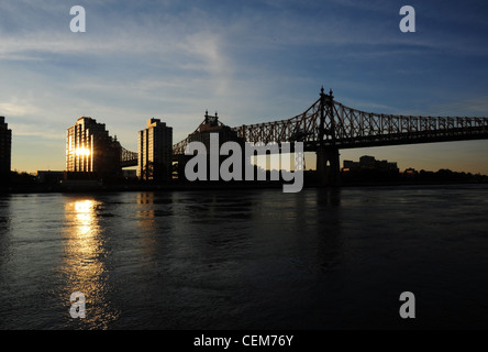 Vista, East River Esplanade a Queensboro Bridge, sunrise riflettendo Roosevelt Appartamenti Isola di acque su East River, New York Foto Stock
