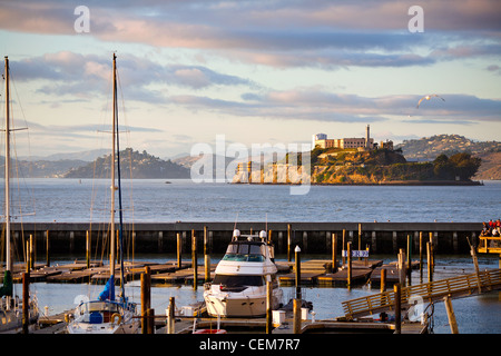 L'impostazione sole illumina Alcatraz visto dal Molo 39 al Fisherman's Wharf di San Francisco, California. Foto Stock