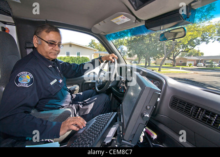 Un Pakistani-American tenente di polizia controlli nel computer di bordo nel suo cruiser in Santa Ana CA. Foto Stock