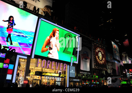 Vista notturna verso West 45th Street, femmina immagini schermi LED sopra Disney Store per sempre 21 Boutique, 7th Avenue, New York Foto Stock