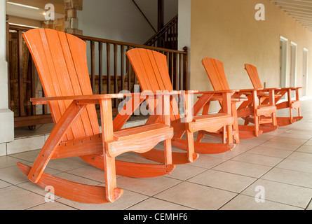 Fila di Orange in legno Sedie a dondolo su un portico (usuale impostazione su un resort tropicale) Foto Stock