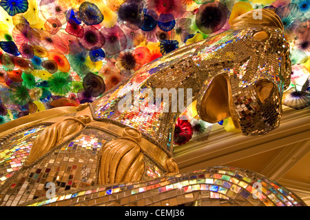 Al di sotto di un soffitto di Dale Chihuly arte del vetro, una buona fortuna cavallo lures gamblers al Bellagio Casino, Las Vegas, Nevada Foto Stock