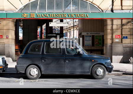 Un tassista si siede in attesa per il suo prossimo cliente al di fuori di Manchester Victoria Rail ferrovia stazione ferroviaria. Foto Stock