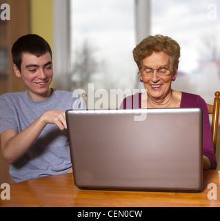 Teen boy cercando di insegnare la nonna di utilizzare un computer portatile Foto Stock