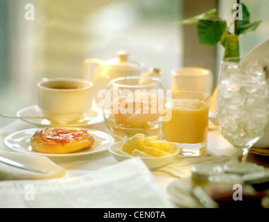Prima colazione continentale in camera presso un hotel, spa, pasticceria con succo di frutta e tè, bicchiere vuoto con ghiaccio e rose in vaso Foto Stock