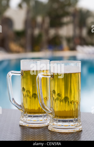 Due boccali da birra da piscina nel resort tropicale Foto Stock